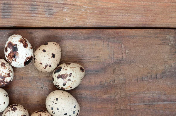 Kwartel eieren op een donker bruine houten oppervlak, bovenaanzicht, lege plaats — Stockfoto