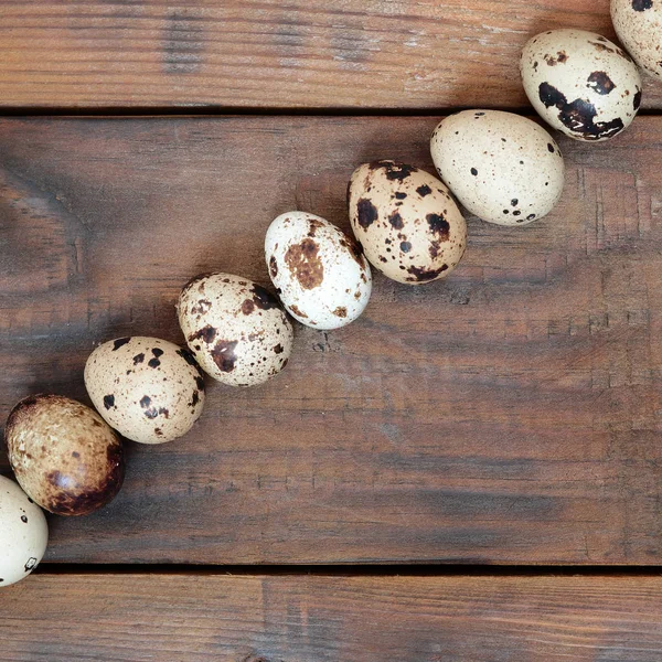 Kwartel eieren op een donker bruine houten oppervlak, bovenaanzicht, lege plaats — Stockfoto