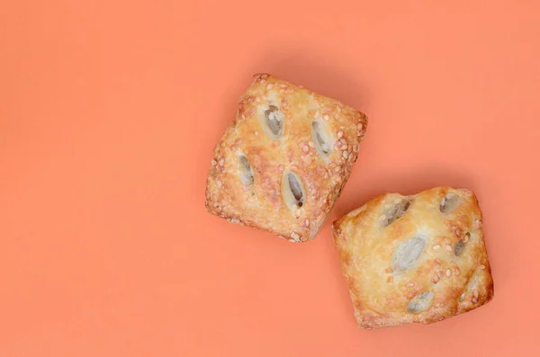 A satisfying meat patty, which combines an airy puff pastry and a delicate pork filling with onions. Baking on an orange background