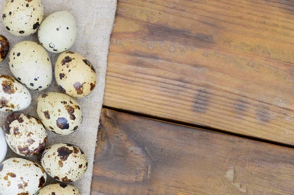 Перепелиные яйца на мешке на темно-коричневой деревянной поверхности, вид сверху , — стоковое фото