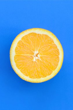 Mavi renkte parlak arka plan üzerinde üstten görünüm bir bir turuncu meyve dilim. Doymuş narenciye doku görüntü