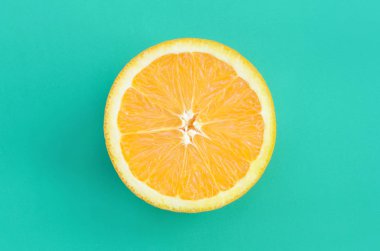 Turkuaz yeşil renkte parlak arka plan üzerinde üstten görünüm bir bir turuncu meyve dilim. Doymuş narenciye doku görüntü