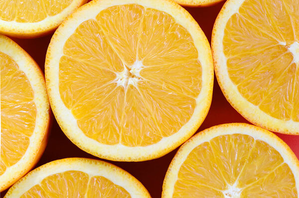 Top view of a several orange fruit slices on bright background in red color. A saturated citrus texture image