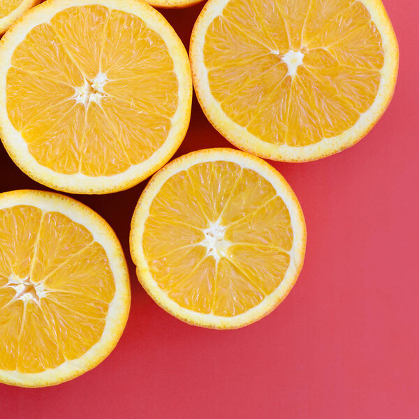 Top view of a several orange fruit slices on bright background in red color. A saturated citrus texture image