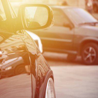 Gri döşeme karede duran siyah parlak araba beyaz tekerlekli, çapraz görünüm