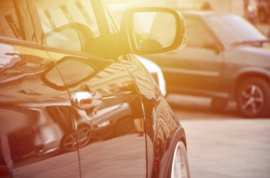 Gri döşeme karede duran siyah parlak araba beyaz tekerlekli, çapraz görünüm