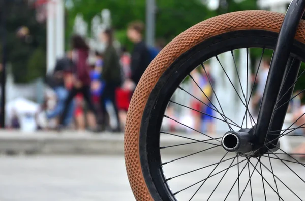 A BMX bike wheel against the backdrop of a blurred street with c