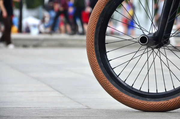 A BMX bike wheel against the backdrop of a blurred street with cycling riders. Extreme Sports Concept