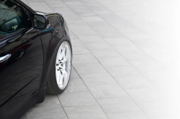 Diagonal vista de un coche negro brillante con ruedas blancas, que sta — Foto de Stock