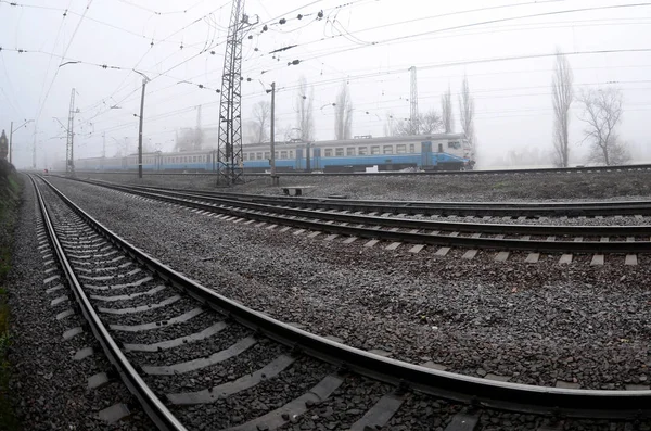 The Ukrainian suburban train rushes along the railway in a misty — Stock Photo, Image