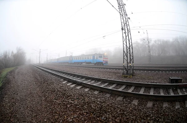乌克兰郊区的火车在一个薄雾的早晨沿着铁路飞驰而过 鱼眼照片与失真增加 — 图库照片