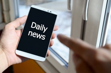 Bir kişi elinde tutuyor bir siyah smartphone ekranda beyaz bir yazıt görür. Güncel haber