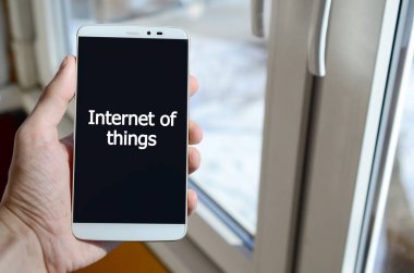 Bir kişi elinde tutuyor bir siyah smartphone ekranda beyaz bir yazıt görür. Şeylerin Internet