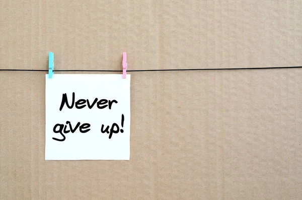 Never give up! Note is written on a white sticker that hangs wit — Stock Photo, Image