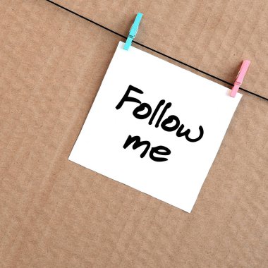 Takip et beni. Not bir clothespin kahverengi karton bir arka plan üzerinde bir ip üzerinde asılı beyaz bir etiket üzerine yazılmış