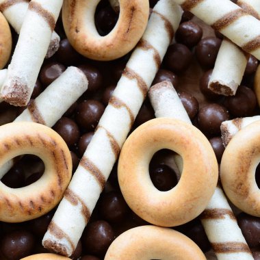 Çıtır çıtır tatlı tübüllerin, çikolata eritme topları ve sarı simit bir sürü yalan bir ahşap yüzeye. Görünümü kapatın