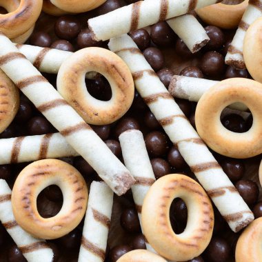 Çıtır çıtır tatlı tübüllerin, çikolata eritme topları ve sarı simit bir sürü yalan bir ahşap yüzeye. Görünümü kapatın