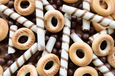 Çıtır çıtır tatlı tübüllerin, çikolata eritme topları ve sarı simit bir sürü yalan bir ahşap yüzeye. Görünümü kapatın