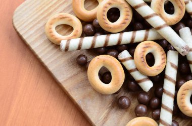 Gevrek tübüllerin, çikolata eritme topları ve simit ahşap yüzeyde yalan. Çeşitli tatlılar karışımı