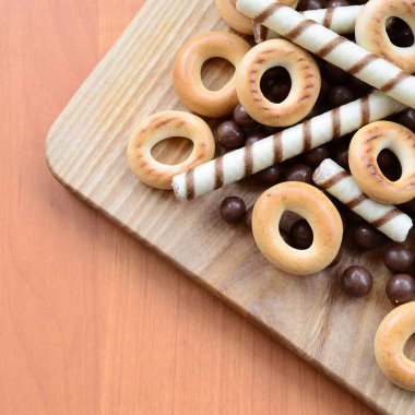 Gevrek tübüllerin, çikolata eritme topları ve simit ahşap yüzeyde yalan. Çeşitli tatlılar karışımı