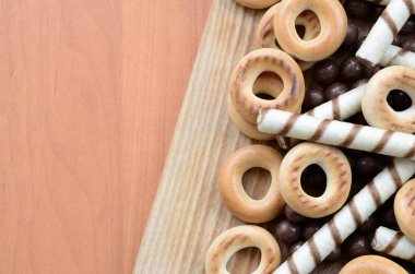 Gevrek tübüllerin, çikolata eritme topları ve simit ahşap yüzeyde yalan. Çeşitli tatlılar karışımı