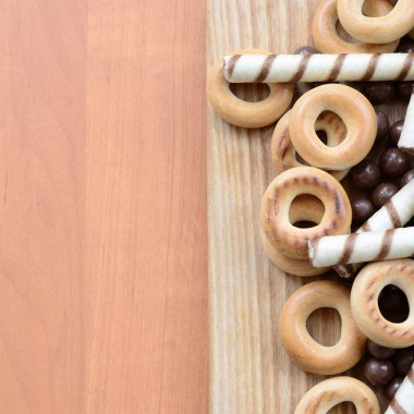 Gevrek tübüllerin, çikolata eritme topları ve simit ahşap yüzeyde yalan. Çeşitli tatlılar karışımı