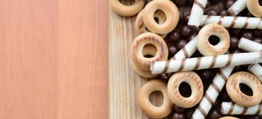 Gevrek tübüllerin, çikolata eritme topları ve simit ahşap yüzeyde yalan. Çeşitli tatlılar karışımı