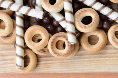 Gevrek tübüllerin, çikolata eritme topları ve simit ahşap yüzeyde yalan. Çeşitli tatlılar karışımı