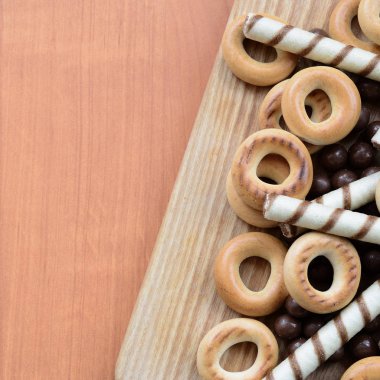 Gevrek tübüllerin, çikolata eritme topları ve simit ahşap yüzeyde yalan. Çeşitli tatlılar karışımı