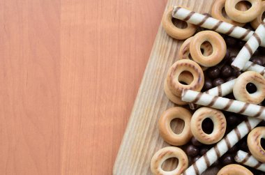 Gevrek tübüllerin, çikolata eritme topları ve simit ahşap yüzeyde yalan. Çeşitli tatlılar karışımı