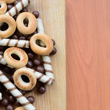 Gevrek tübüllerin, çikolata eritme topları ve simit ahşap yüzeyde yalan. Çeşitli tatlılar karışımı