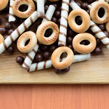 Gevrek tübüllerin, çikolata eritme topları ve simit ahşap yüzeyde yalan. Çeşitli tatlılar karışımı