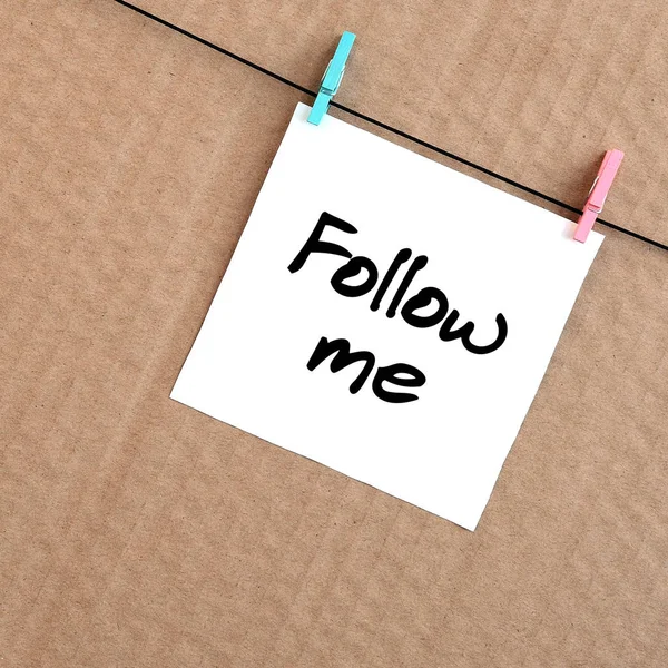 Takip et beni. Not bir clothespin kahverengi karton bir arka plan üzerinde bir ip üzerinde asılı beyaz bir etiket üzerine yazılmış