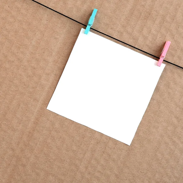 Cartão branco em branco na corda em um fundo de papelão marrom. Creati. — Fotografia de Stock