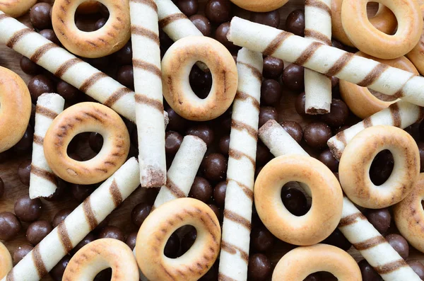 Çıtır çıtır tatlı tübüllerin, çikolata eritme topları ve sarı simit bir sürü yalan bir ahşap yüzeye. Görünümü kapatın