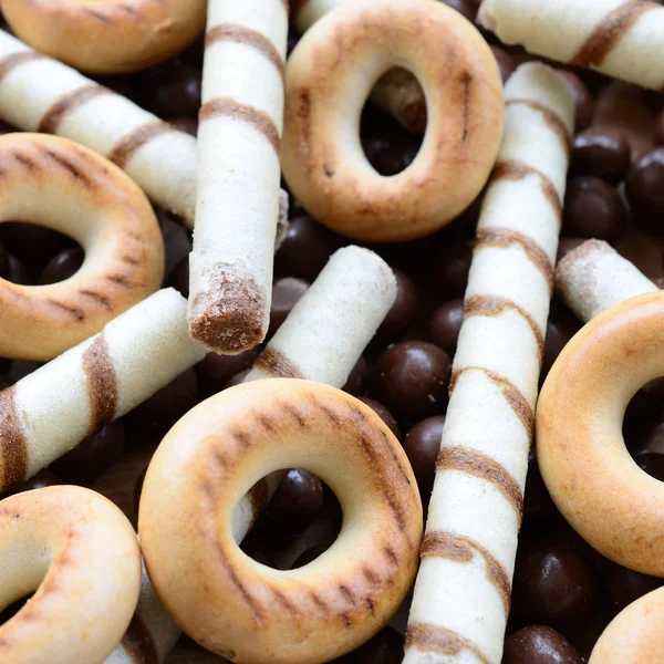 Çıtır çıtır tatlı tübüllerin, çikolata eritme topları ve sarı simit bir sürü yalan bir ahşap yüzeye. Görünümü kapatın