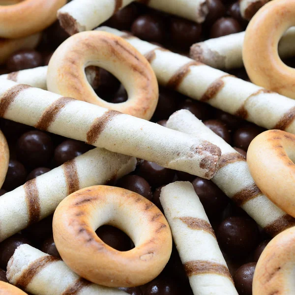 Çıtır çıtır tatlı tübüllerin, çikolata eritme topları ve sarı simit bir sürü yalan bir ahşap yüzeye. Görünümü kapatın