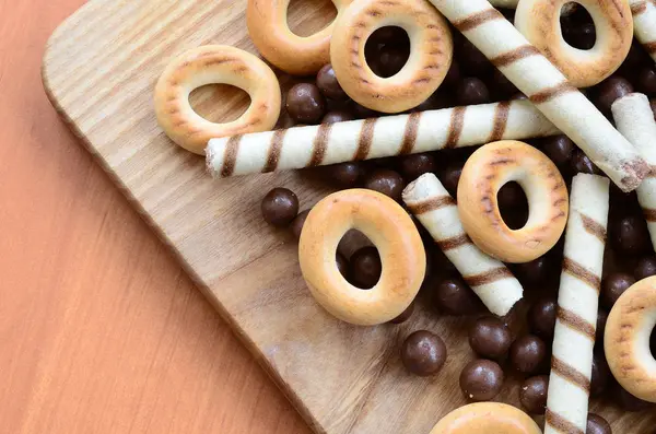 Gevrek tübüllerin, çikolata eritme topları ve simit ahşap yüzeyde yalan. Çeşitli tatlılar karışımı