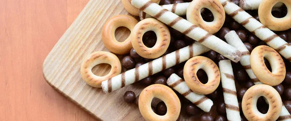 Gevrek tübüllerin, çikolata eritme topları ve simit ahşap yüzeyde yalan. Çeşitli tatlılar karışımı