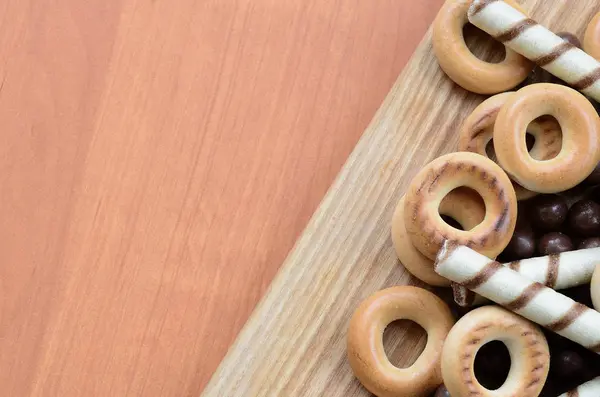 Gevrek tübüllerin, çikolata eritme topları ve simit ahşap yüzeyde yalan. Çeşitli tatlılar karışımı