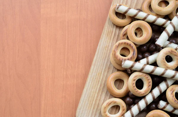 Gevrek tübüllerin, çikolata eritme topları ve simit ahşap yüzeyde yalan. Çeşitli tatlılar karışımı