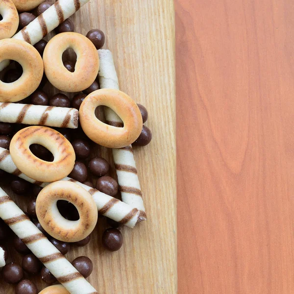 Gevrek tübüllerin, çikolata eritme topları ve simit ahşap yüzeyde yalan. Çeşitli tatlılar karışımı