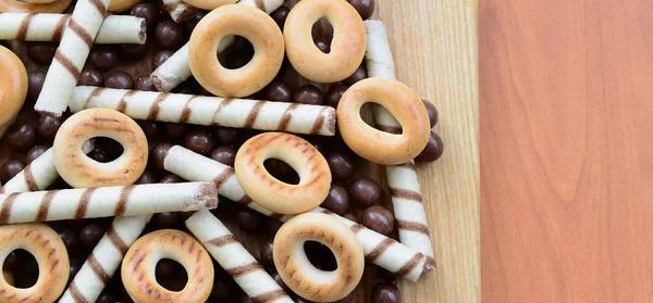 Gevrek tübüllerin, çikolata eritme topları ve simit ahşap yüzeyde yalan. Çeşitli tatlılar karışımı