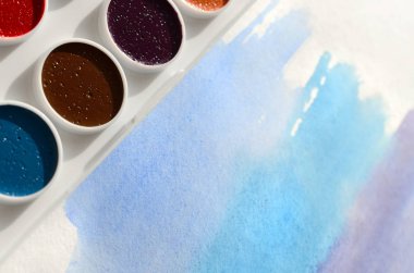 Bir mavi vuruş şeklinde soyut bir suluboya çizim gösteren kağıt üzerine suluboya yeni bir dizi yatıyor. Gençler arasında amatör resim kavramı