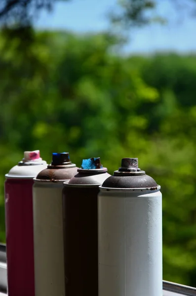 A few used aerosol paint sprayers lie on the windowsill in the workshop of a graffiti artist. The concept of street art and illegal drawing on the walls. Youth hobby