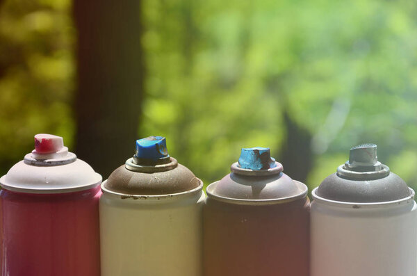 A few used aerosol paint sprayers lie on the windowsill in the workshop of a graffiti artist. The concept of street art and illegal drawing on the walls. Youth hobby