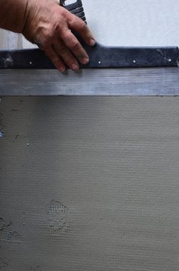 Ev yenilenen araçları sıvama duvar ile eski bir işçi elleri. Sıvacı yenilenen açık duvar ve spatula ve alçı ile köşeleri. Duvar izolasyonu. İnşaat bitirme işleri