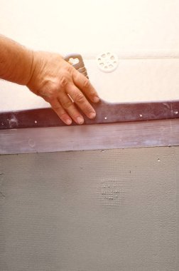 Ev yenilenen araçları sıvama duvar ile eski bir işçi elleri. Sıvacı yenilenen açık duvar ve spatula ve alçı ile köşeleri. Duvar izolasyonu. İnşaat bitirme işleri