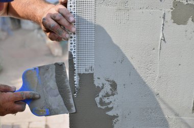 Ev yenilenen araçları sıvama duvar ile eski bir işçi elleri. Sıvacı yenilenen açık duvar ve spatula ve alçı ile köşeleri. Duvar izolasyonu. İnşaat bitirme işleri