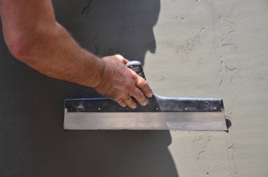 Ev yenilenen araçları sıvama duvar ile eski bir işçi elleri. Sıvacı yenilenen açık duvar ve spatula ve alçı ile köşeleri. Duvar izolasyonu. İnşaat bitirme işleri